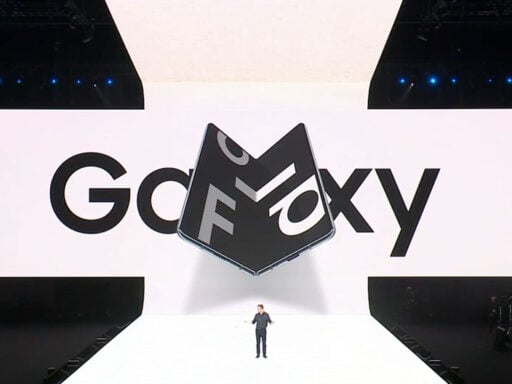 Escenario blanco donde se hizo la presentación del dispositivo. Se ve un hombre presentando y la imagen del Galaxy Fold a su espaldar.